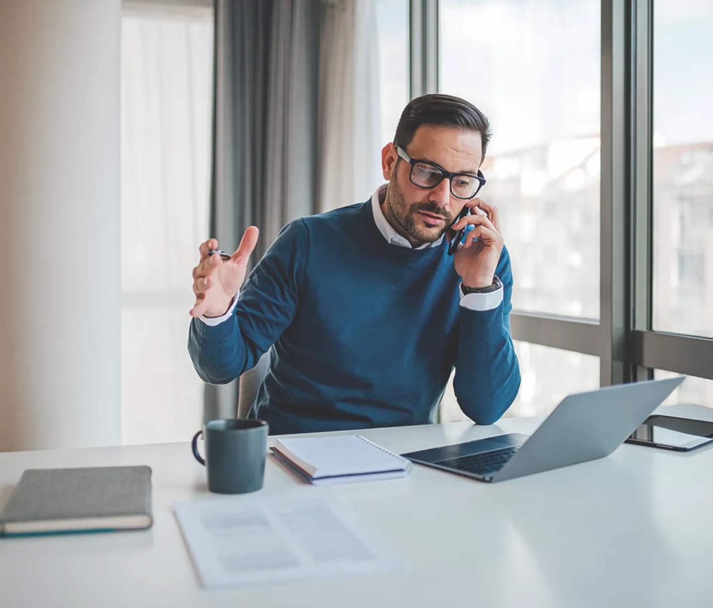 Man sitting at laptop talking on the phone