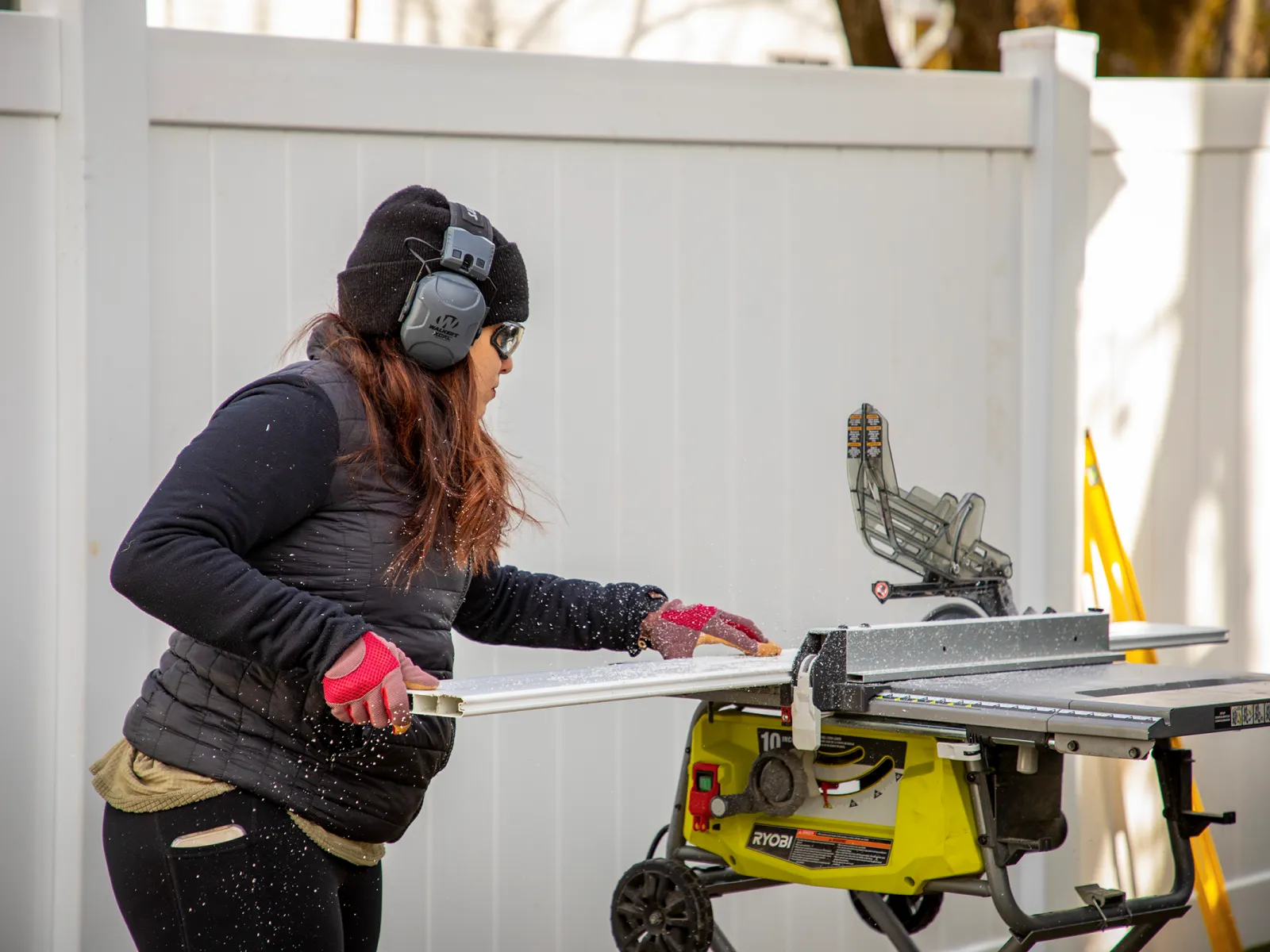 woman installing a white vinyl privacy fence